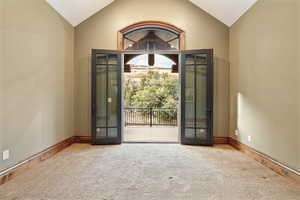 Carpeted entryway with french doors and vaulted ceiling