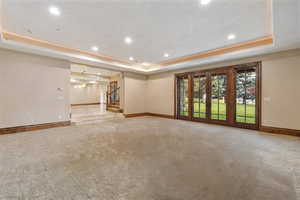 Unfurnished room with light colored carpet and a raised ceiling