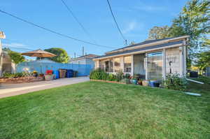 Rear view of property with central AC, a sunroom, and a lawn