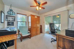 Carpeted home office featuring ceiling fan