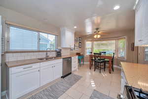 Kitchen with white cabinets, quartz, light tile patterned flooring, sink, tasteful backsplash, and appliances with stainless steel finishes