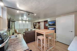 Kitchen with track lighting, a textured ceiling, sink, and laminate wood/style flooring.