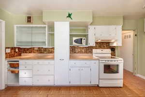 Kitchen with white cabinets, tasteful backsplash, white appliances, and light parquet style floors