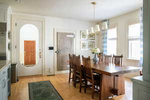 Dining room with light wood-type flooring and a notable chandelier