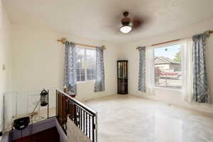 Interior space featuring ceiling fan, a textured ceiling, and a wealth of natural light