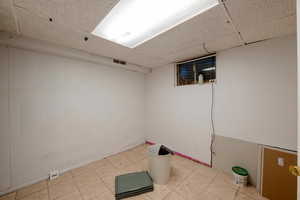 Basement with a paneled ceiling and tile patterned floors