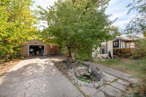 View of property hidden behind natural elements with a garage and an outbuilding