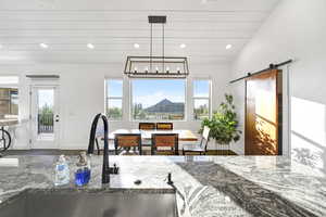 Kitchen featuring lofted ceiling, wood-type flooring, dark stone countertops, sink, and a barn door