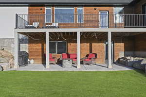 Back of house with an outdoor living space, a lawn, a balcony, and a patio area