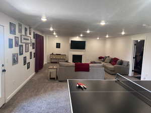 Game room featuring dark colored carpet and a textured ceiling