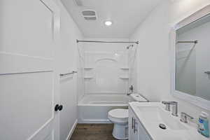 Full bathroom with wood-type flooring, bathtub / shower combination, vanity, and toilet