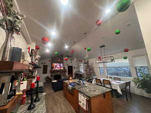 Kitchen featuring high vaulted ceiling, wood-type flooring, sink, dark stone counters, and a fireplace