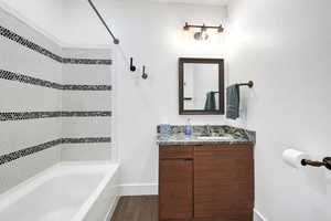 Bathroom with wood-type flooring, tiled shower / bath combo, and vanity