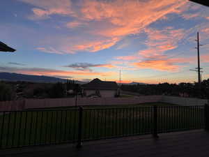 Deck at dusk featuring a mountain view and a lawn