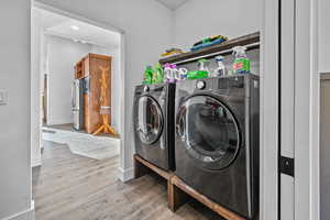 Laundry area with hardwood / wood-style flooring and washer and dryer