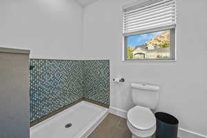 Bathroom featuring tile patterned floors, toilet, and a shower