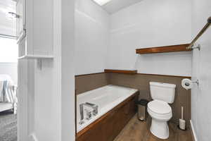 Bathroom with tile walls, toilet, and wood-type flooring