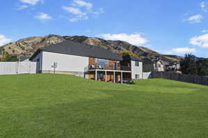 Back of property with a mountain view and a lawn