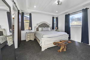 Bedroom featuring a raised ceiling and a barn door