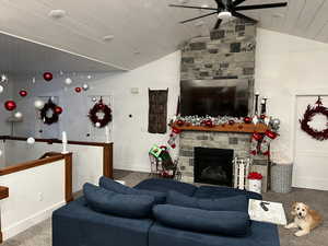 Living room with ceiling fan, carpet flooring, a fireplace, and vaulted ceiling