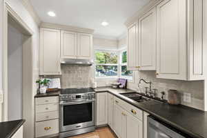 Kitchen featuring ornamental molding, sink, tasteful backsplash, light hardwood / wood-style flooring, and appliances with stainless steel finishes