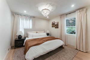 Bedroom with an inviting chandelier and light hardwood / wood-style flooring