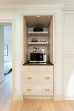 Bar with ornamental molding and light hardwood / wood-style flooring