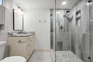 Bathroom featuring vanity, a shower with door, and toilet