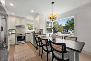 Kitchen with appliances with stainless steel finishes, pendant lighting, crown molding, and tasteful backsplash