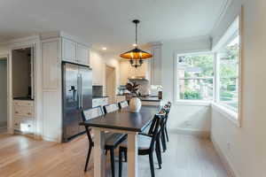 Dining area with ornamental molding and light wood-type flooring