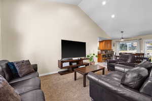 Carpeted living room with high vaulted ceiling and ceiling fan