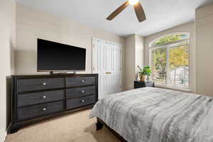 Bedroom featuring light carpet, a textured ceiling, and ceiling fan