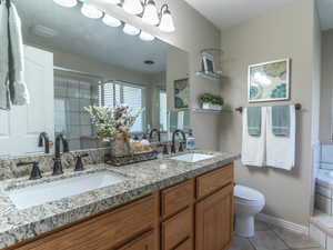 Primary Bathroom featuring tile patterned flooring, a sink, a bath, and toilet
