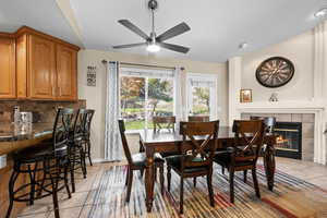 Dining area with light tile patterned flooring, ceiling fan, and a tile fireplace