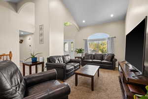 Carpeted living room with french doors and high vaulted ceiling