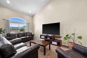 Carpeted living room featuring high vaulted ceiling