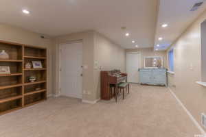 Interior space featuring light colored carpet, visible vents, and recessed lighting