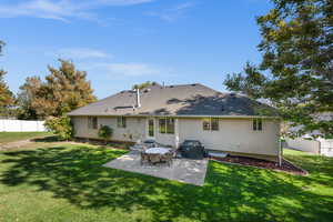 Back of house featuring a lawn and a patio area