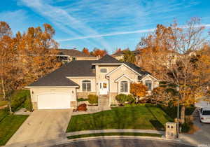 Single story home with a garage, a front lawn, stone siding, stucco siding, and concrete driveway