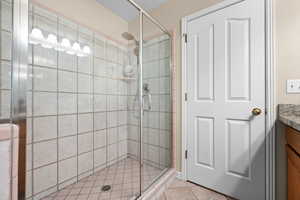 Bathroom featuring vanity, a shower with door, and tile patterned floors
