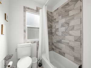 Bathroom featuring shower / bath combination with curtain and toilet