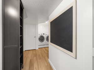 Washroom featuring a textured ceiling, light wood-type flooring, and washer and dryer