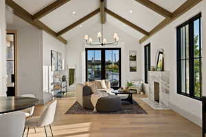 Living room with beam ceiling, a premium fireplace, high vaulted ceiling, an inviting chandelier, and light wood-type flooring