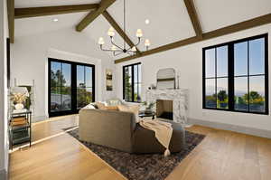 Living room featuring hardwood / wood-style flooring, a notable chandelier, a high end fireplace, and high vaulted ceiling