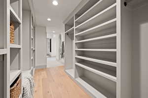 Walk in closet with light hardwood / wood-style flooring