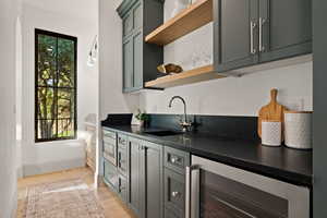 Kitchen featuring stainless steel microwave, light hardwood / wood-style flooring, wine cooler, and sink