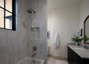 Full bathroom featuring tile patterned flooring, vanity, tiled shower / bath combo, and toilet