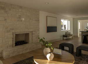 Living room with a stone fireplace and hardwood / wood-style floors