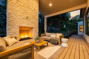 Patio terrace at dusk with an outdoor living space with a fireplace and a wooden deck