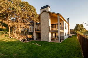 Back of house featuring central air condition unit, a patio, a yard, and a balcony